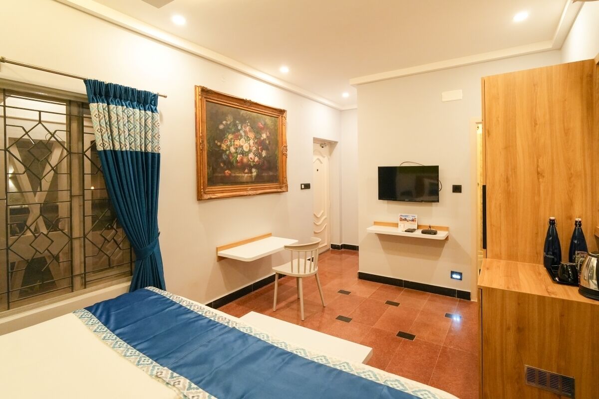 Une chambre d’hôtel comprenant un lit, un bureau, une chaise, un téléviseur et un comptoir d’accueil en bois.