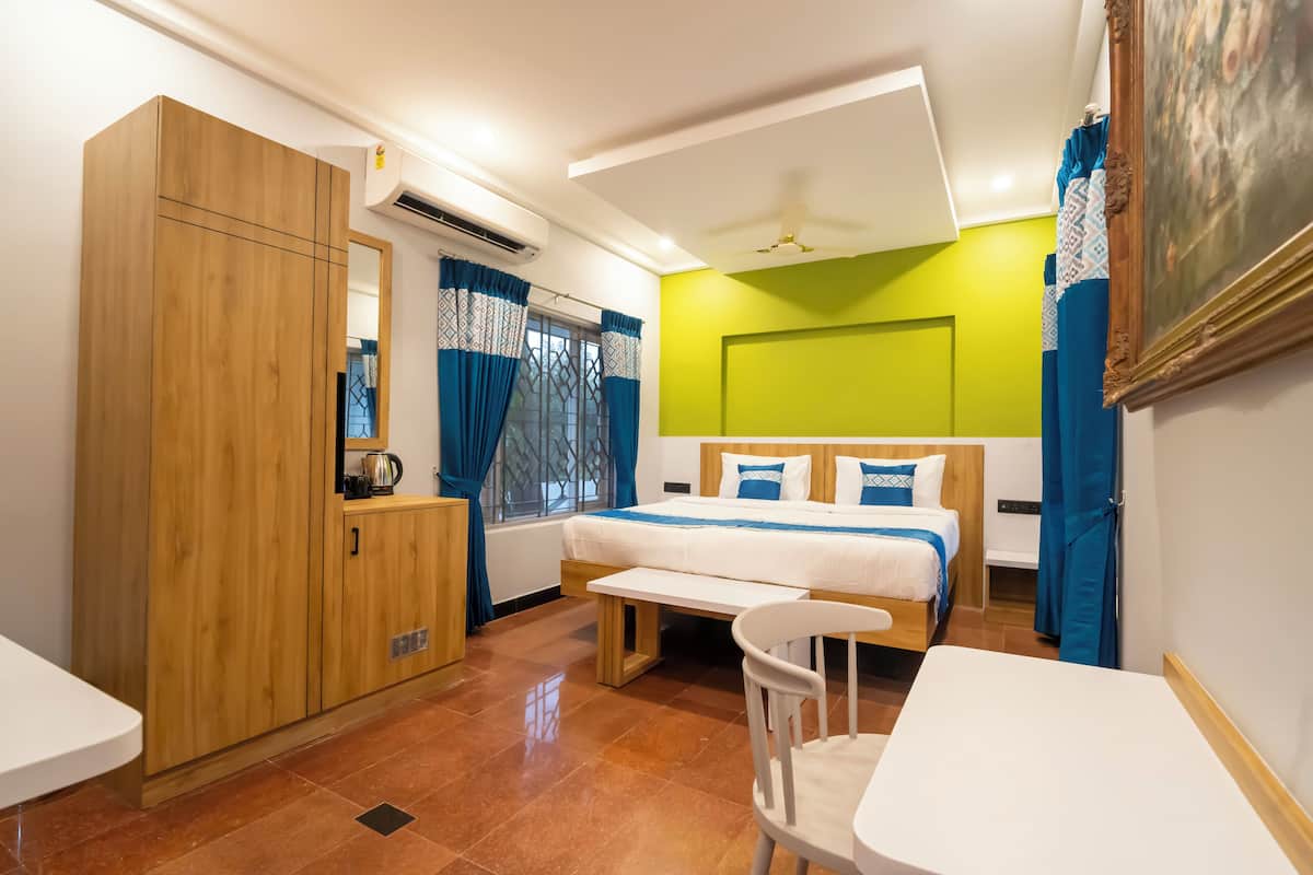 Una habitación de hotel con cama, armario de madera, banco, mesita y silla.