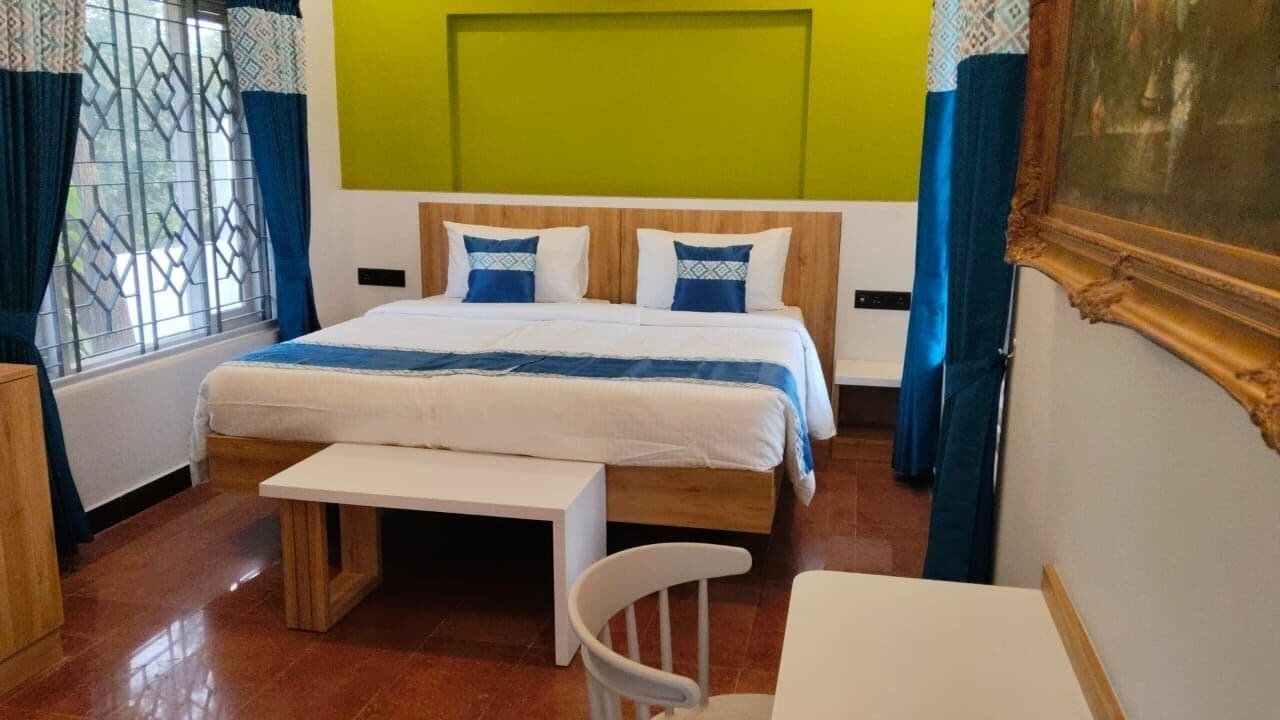 Hotellihuone, jossa on sänky, penkki, tuoli ja pöytä.