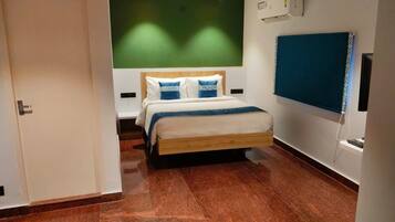 Een hotelkamer met een houten bed, een groene wand, een blauw gordijn en een wandtelevisie.