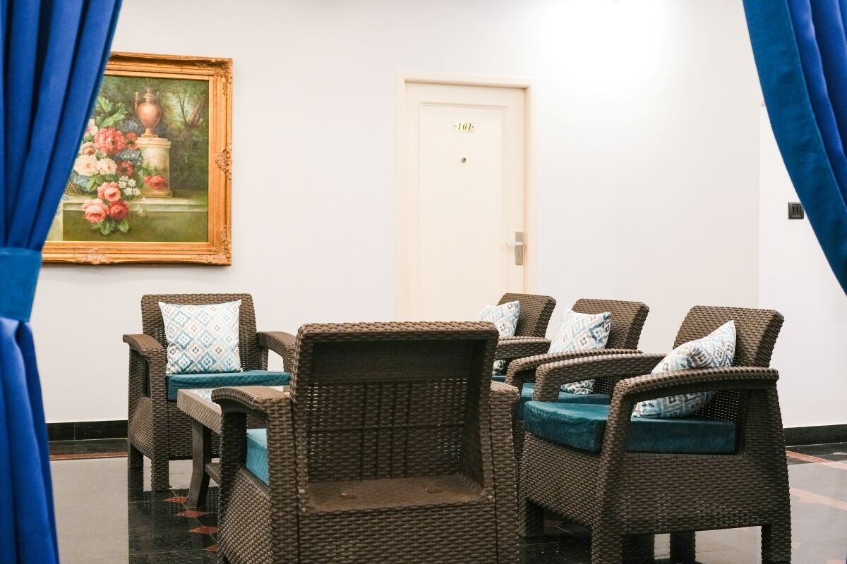 A room with wicker furniture, a door with a number, and a painting on the wall.