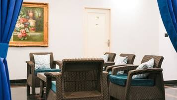 A room with wicker furniture, a door with a number, and a painting on the wall.