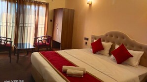 A hotel room with a bed, a desk, and a chair. There is an air conditioning unit on the wall. - Maa Paradise World (Alipurduar)
