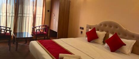A hotel room with a bed, a desk, and a chair. There is an air conditioning unit on the wall.