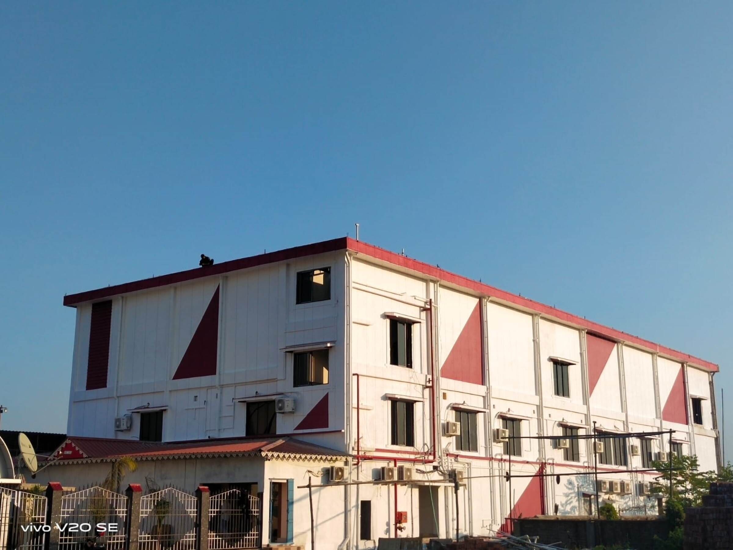 A multi-story building with a red and white facade, multiple windows, and a gated entrance.