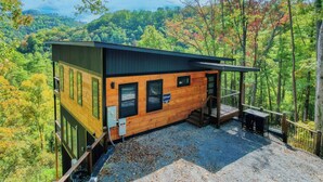 Eine Holzhütte mit Balkon und Blick auf ein bewaldetes Gebirge.