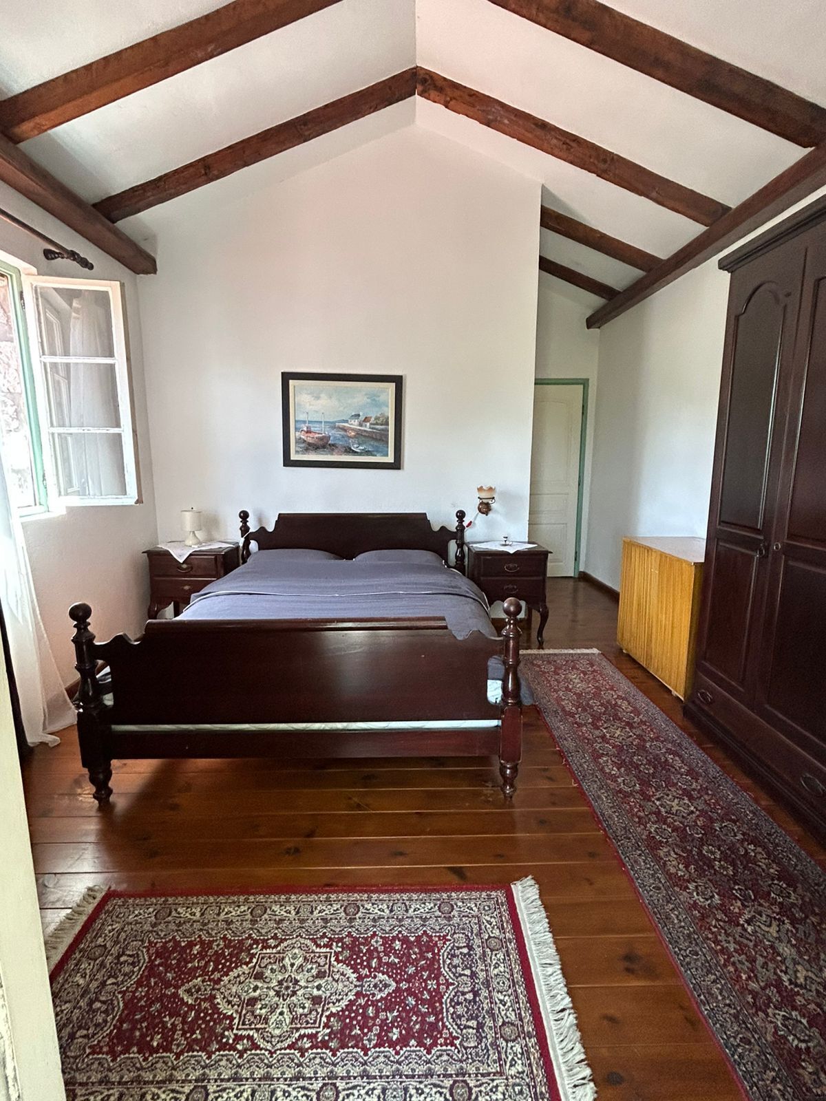 Un dormitorio con cama de madera, un cuadro en la pared y un amplio armario.