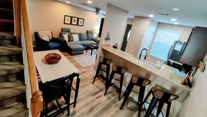 Una cocina moderna con barra, una mesa de comedor con sillas y una sala de estar con sofá y mesa de centro.