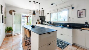 A modern kitchen with a central island, white cabinetry, a black countertop, and pendant lighting. - Beautiful home in Graveson (Graveson)