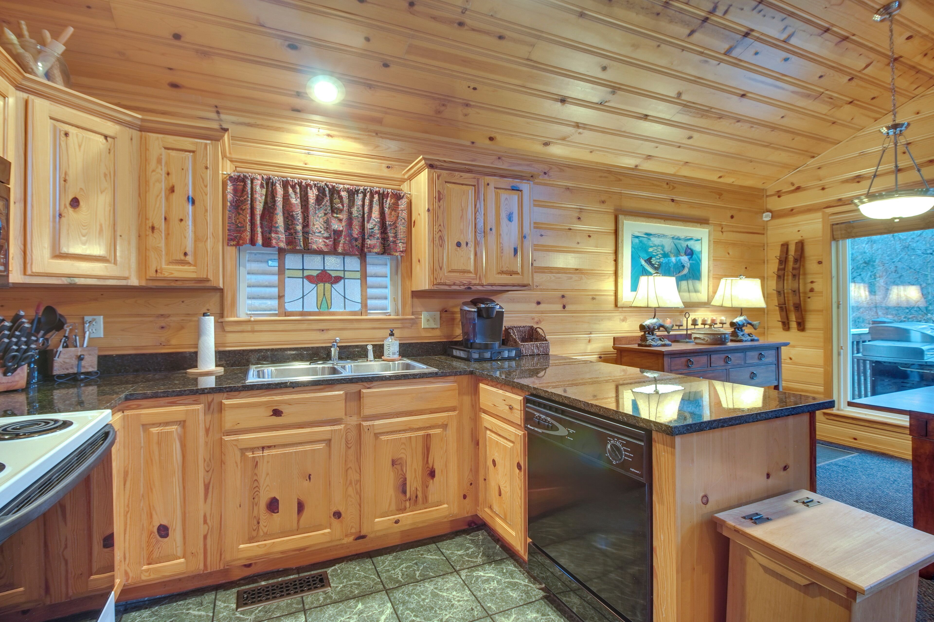Una cocina amplia con armarios de madera, una isla central, lavavajillas y un ventanal con vistas.