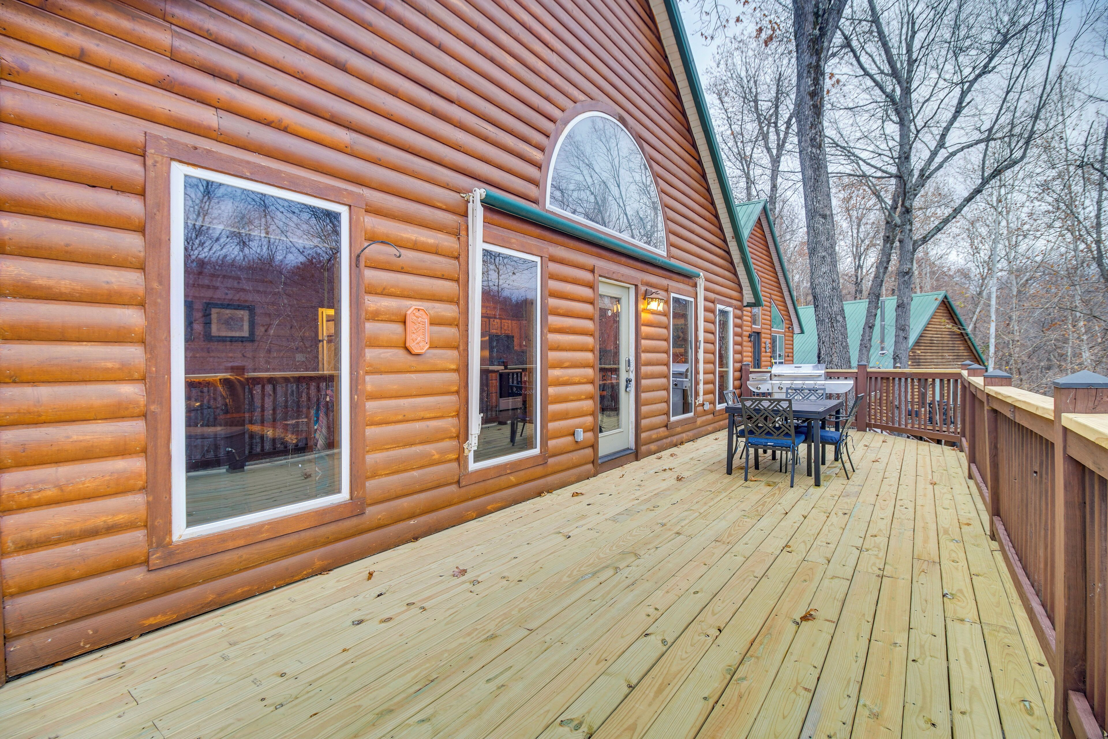 A log cabin with a deck, large windows, and a dining area.