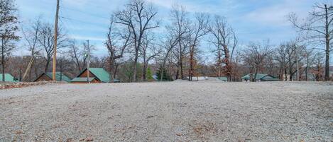 A gravel parking area with several green-roofed cabins in a wooded setting.