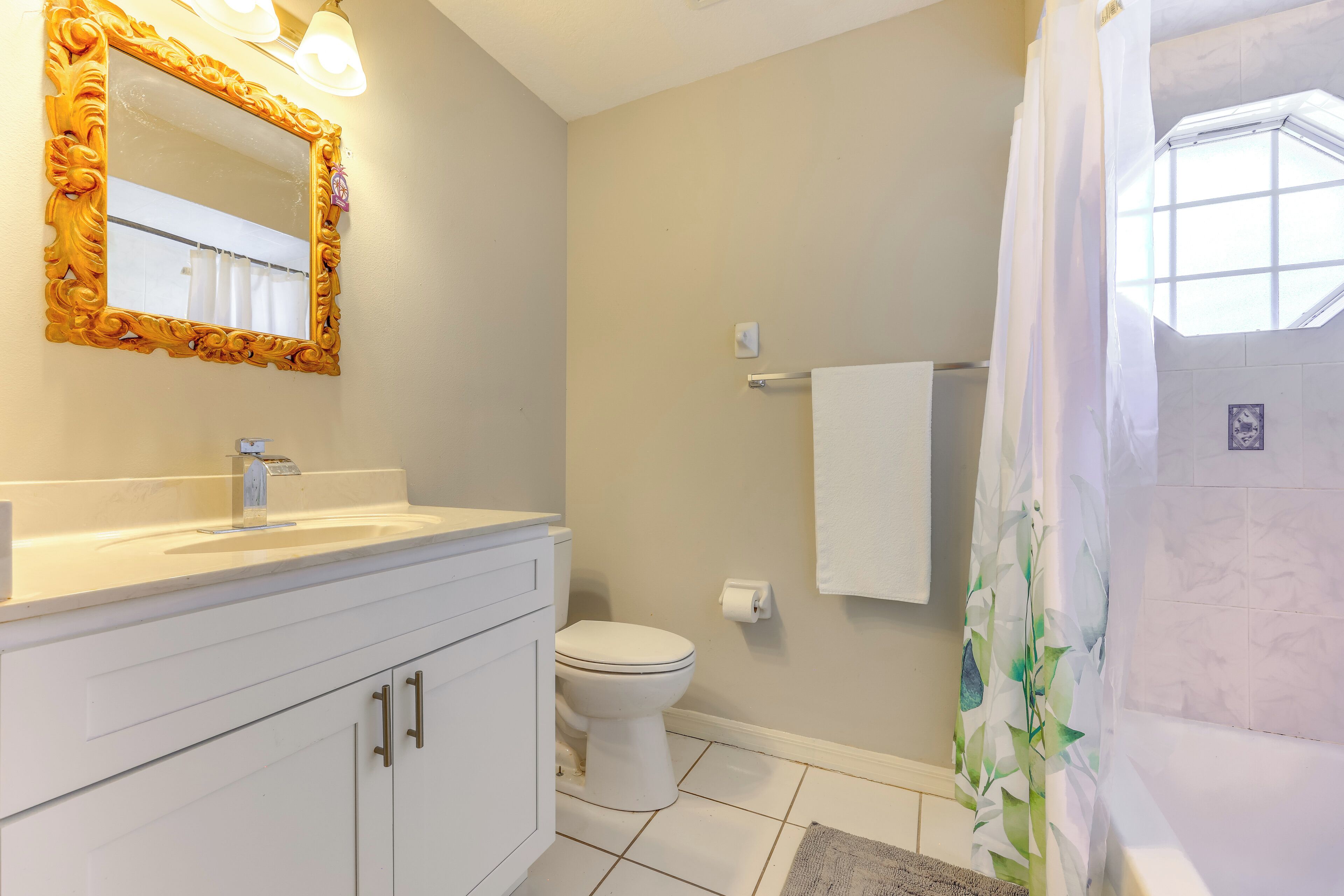 A bathroom with a white sink, mirror, and toilet.