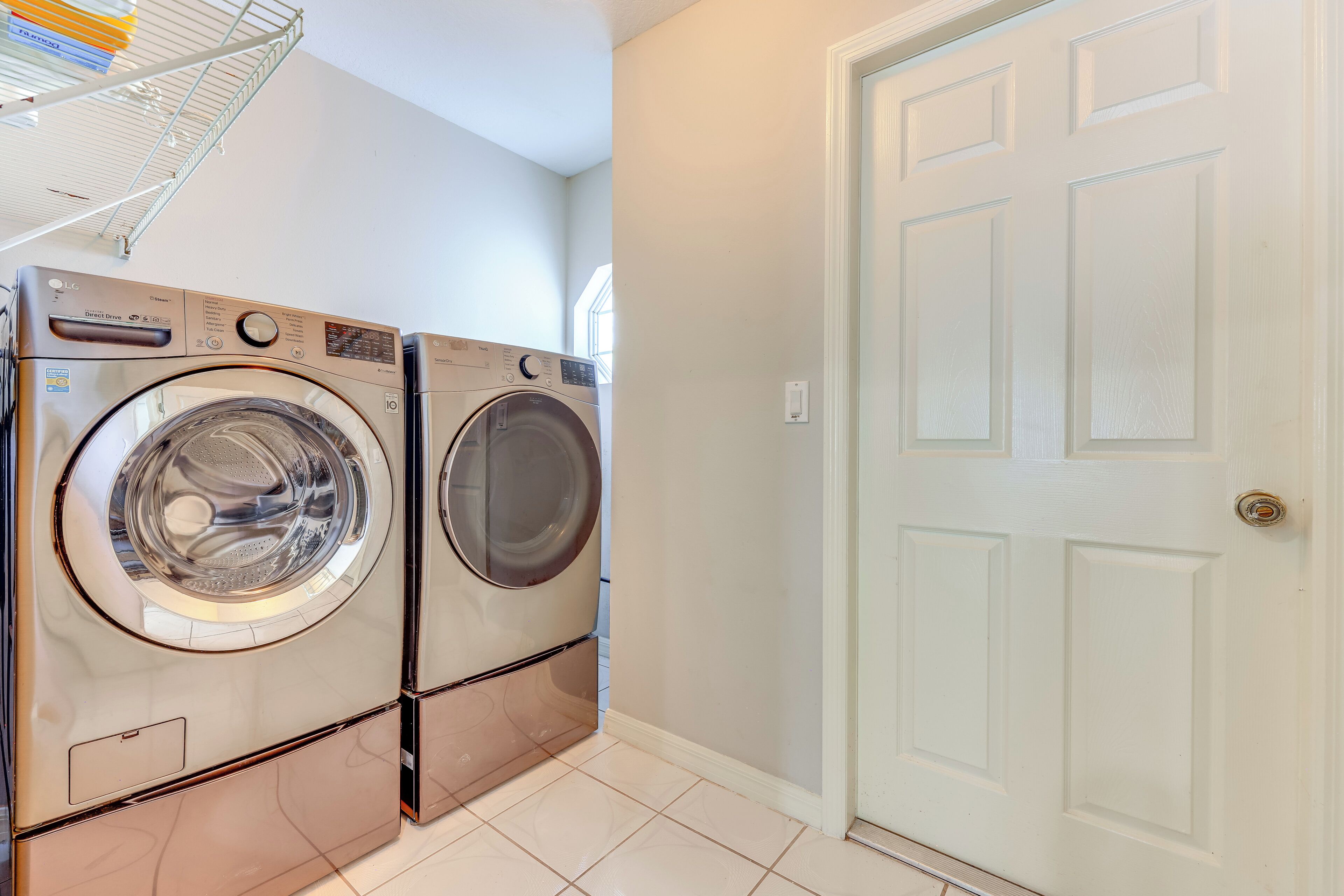 A laundry room with two front-loading washing machines and a white door.