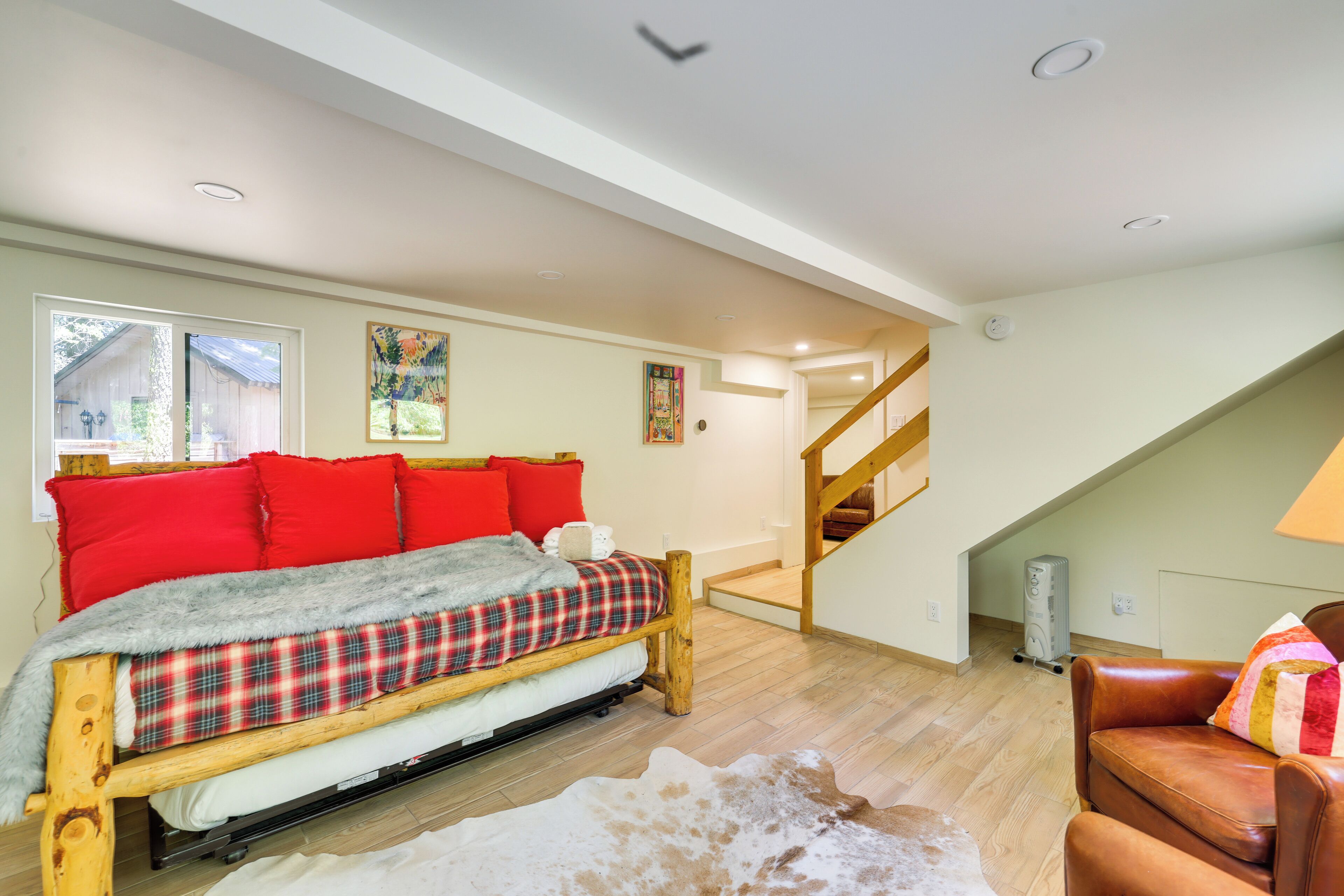 A bedroom with a bed, a wooden staircase, and a cowhide rug.