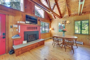 Un intérieur en bois avec une cheminée, une table à manger et de grandes fenêtres.