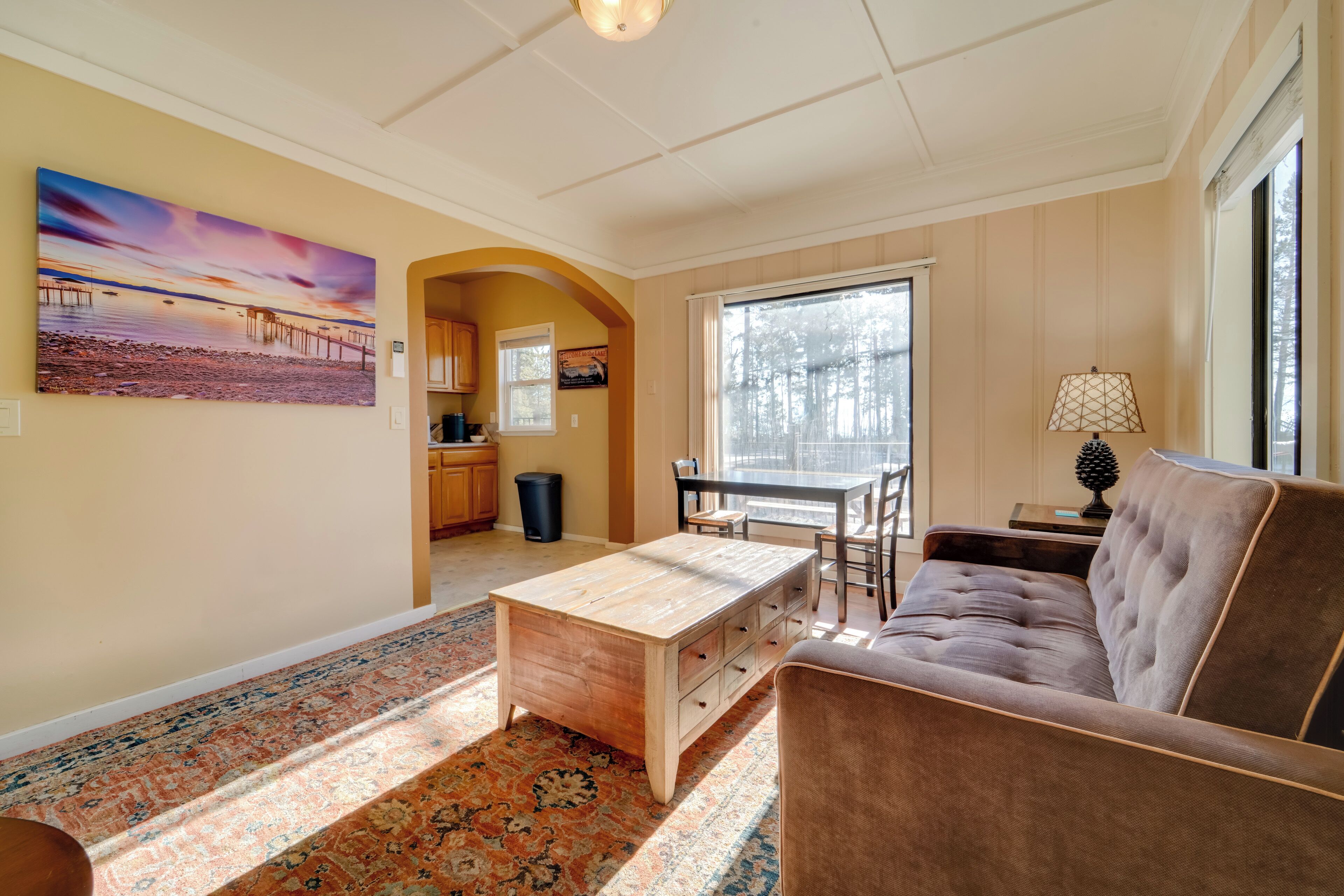 A living room with a sofa, a coffee table, a rug, and a painting on the wall.