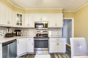 Una cocina moderna con armarios blancos, electrodomésticos de acero inoxidable y salpicadero de azulejos.