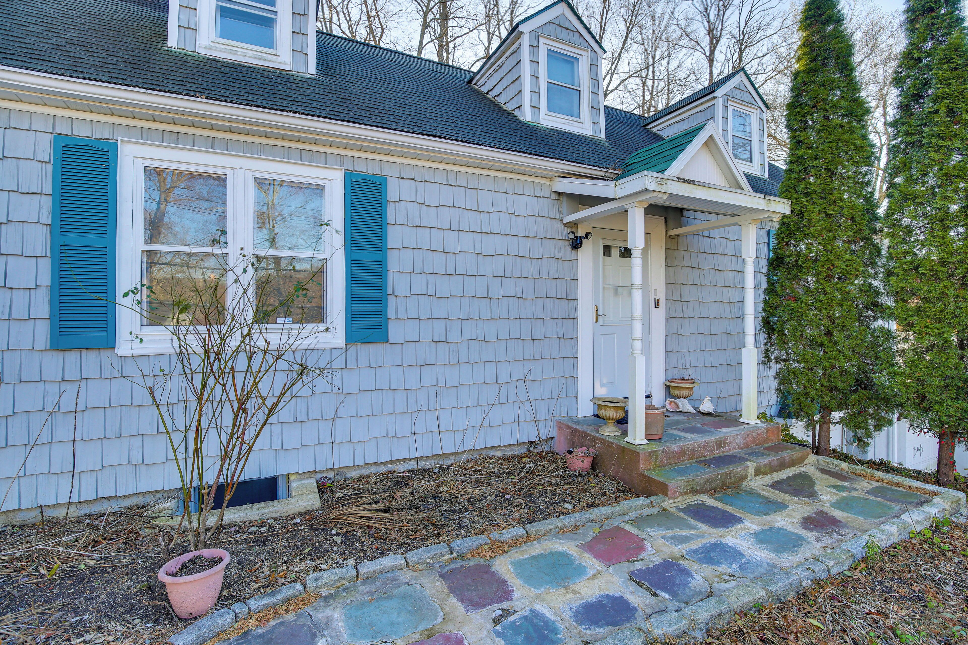 A house with a front porch, a small garden area with a potted plant, and a stone pathway leading to the entrance.