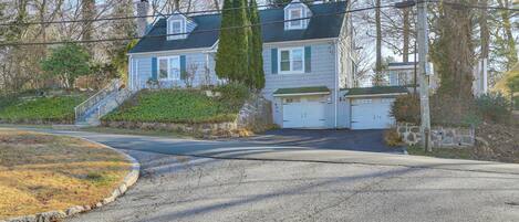 A two-story house with a garage, a staircase leading to the front door, and a driveway curving around the property.