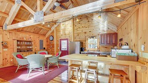 Interior de una cabaña de madera con comedor, cocina y barra.
