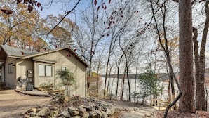 Een chalet met een pad van stenen dat uitkomt op een houten terras met uitzicht op een meer.