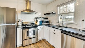 A modern kitchen with stainless steel appliances, white cabinetry, and a window providing natural light. - Dog-friendly Home w/ Patio & Yard in Greeley (Greeley)