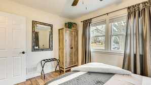 A bedroom with a bed, a wardrobe, a mirror, a ceiling fan, and a window with curtains. - Dog-friendly Home w/ Patio & Yard in Greeley (Greeley)