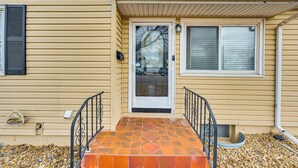 A house with a front door, two windows, and a small porch with a tiled floor. - Dog-friendly Home w/ Patio & Yard in Greeley (Greeley)