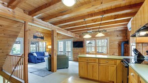 L’intérieur d’un chalet en bois comprend une cuisine, un coin repas et un salon avec un canapé et un téléviseur.