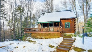 Une cabane avec une façade en bois, une véranda et un escalier menant à l’entrée.