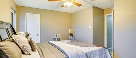 A bedroom with a bed, a ceiling fan, a dresser, and a door.