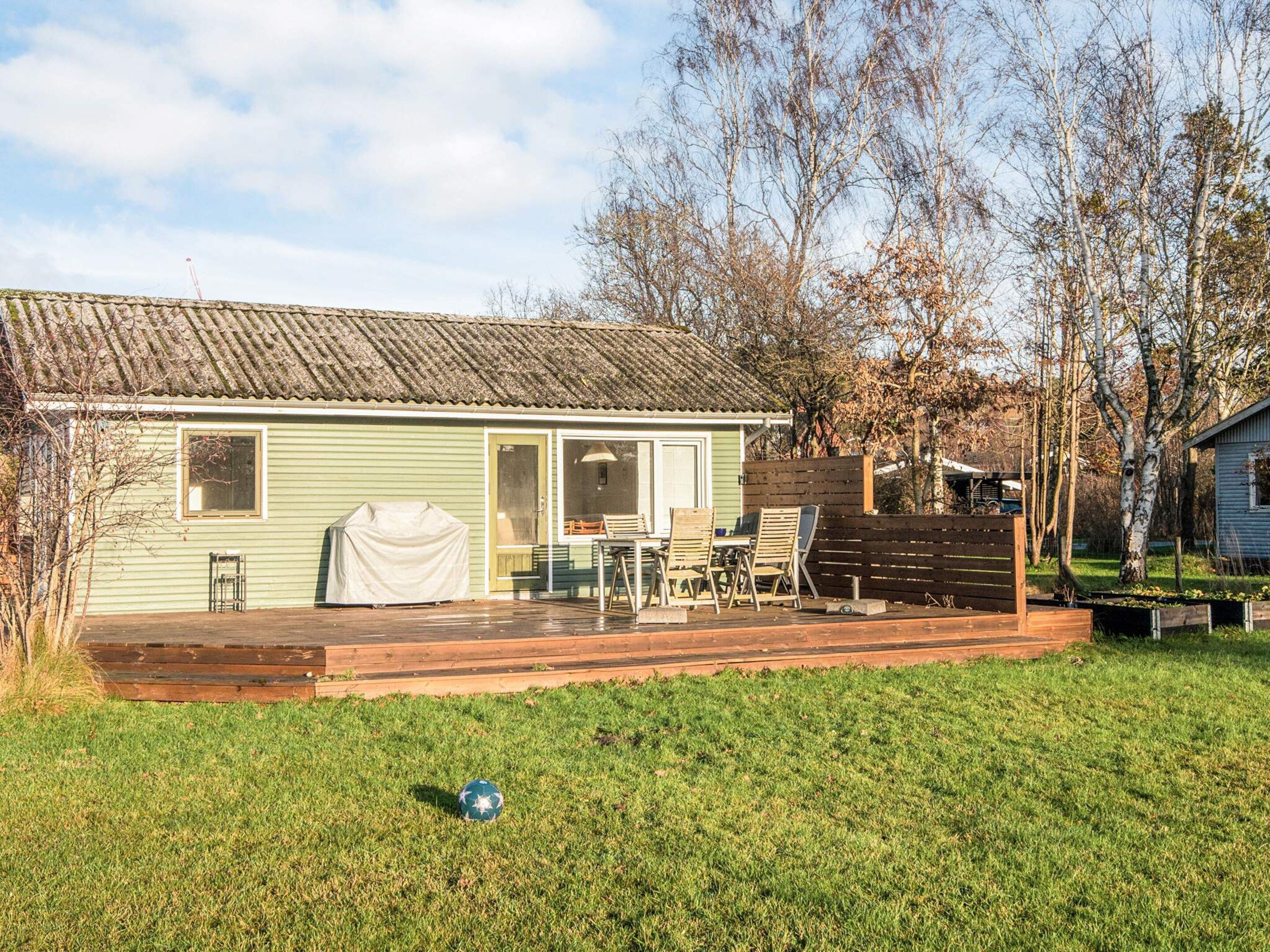 A single-story house with a porch, a covered grill, and a small deck.