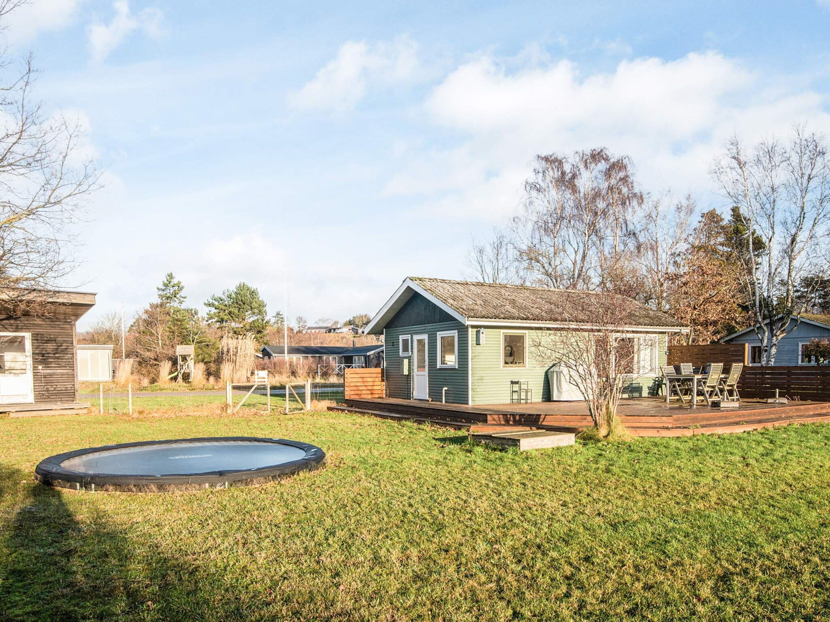 A residential area with a small house, a trampoline, and a fenced yard.