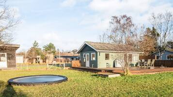 A residential area with a small house, a trampoline, and a fenced yard.