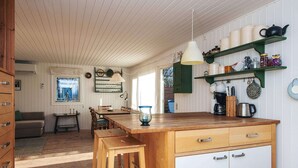 A kitchen with wooden cabinets, a dining table, and a coffee station.