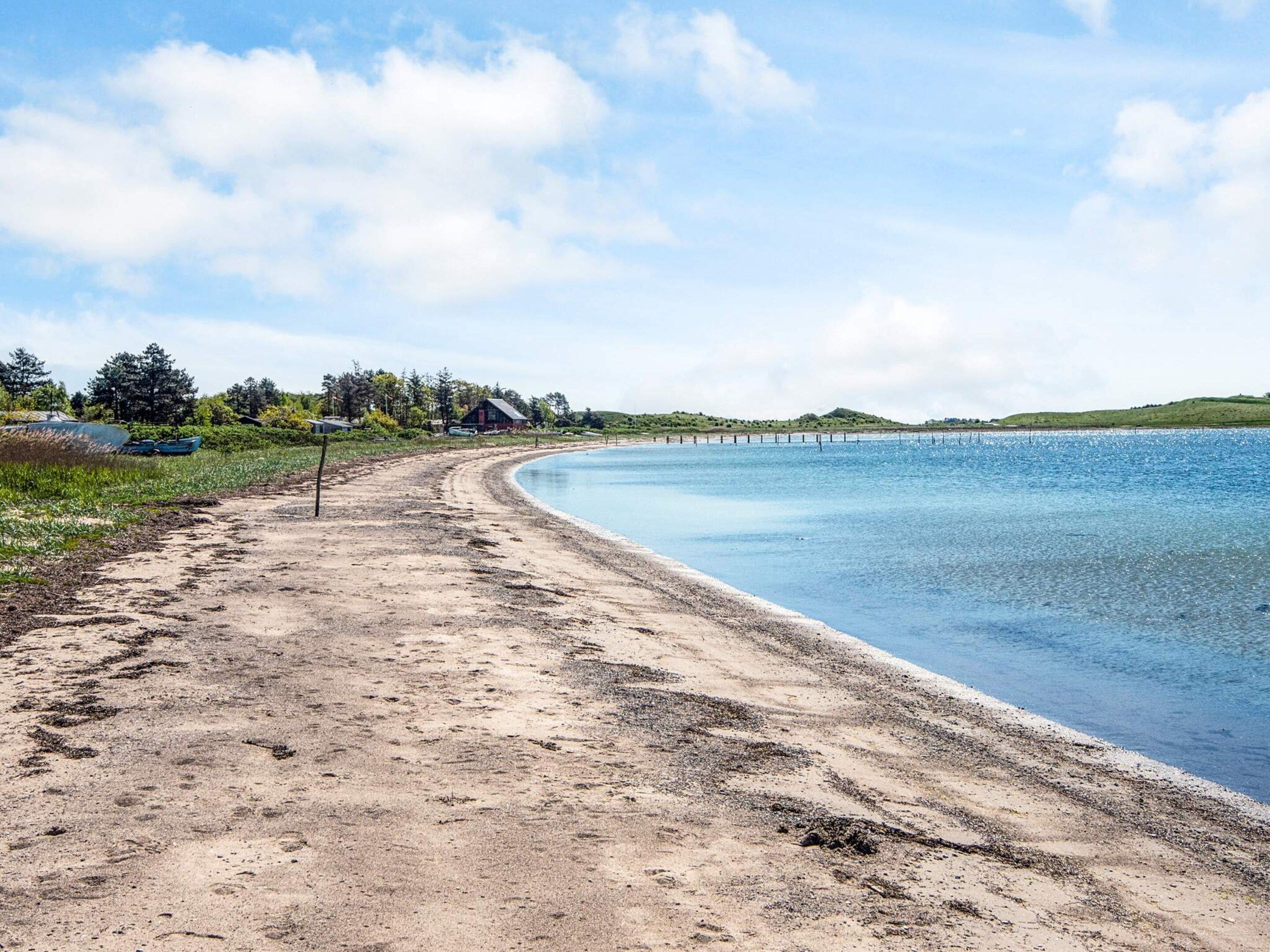 A sandy beach with a clear blue sky and calm water.