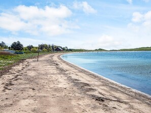 A sandy beach with a clear blue sky and calm water. - 4 Person Holiday Home in Knebel (Knebel)