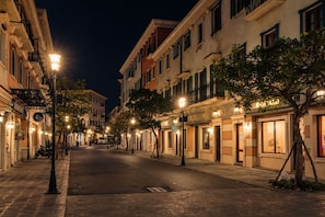 A nighttime street scene with buildings, street lamps, and parked motorcycles. - The Nice Hotel Phu Quoc - Fireworks & Ocean view (Phu Quoc)