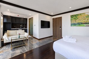 A hotel room with a bed, a sofa, a small table, a TV, and a painting on the wall. - The Nice Hotel Phu Quoc - Fireworks & Ocean view (Phu Quoc)