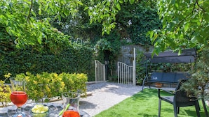 A patio with a table set for a meal, a bench, and a gate leading to a garden. - Holiday House Genoveffa (Massa Lubrense)
