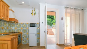A kitchen with wooden cabinets, a microwave, and a refrigerator. - Holiday House Genoveffa (Massa Lubrense)