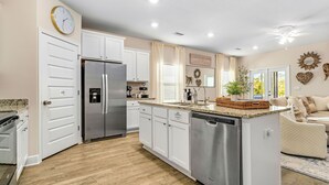 Uma cozinha moderna com armários brancos, eletrodomésticos de aço inoxidável e uma ilha central.