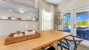 Uma área de refeições com mesa de madeira, bandeja de vime e dois castiçais de vidro.