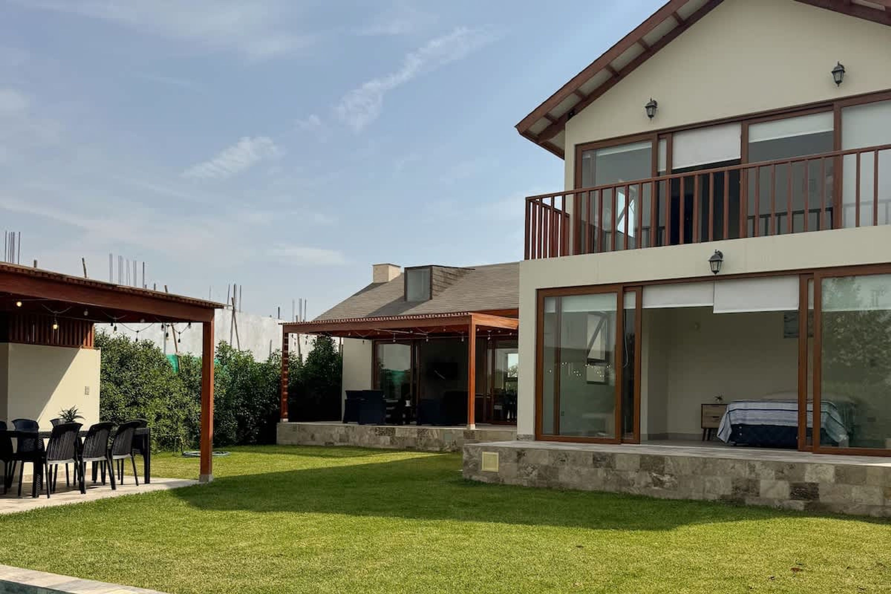 Una casa moderna de dos pisos con un porche cubierto, un balcón y un césped bien cuidado.