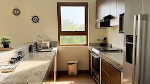 Una cocina moderna con un amplio ventanal, electrodomésticos de acero inoxidable y armarios de madera.