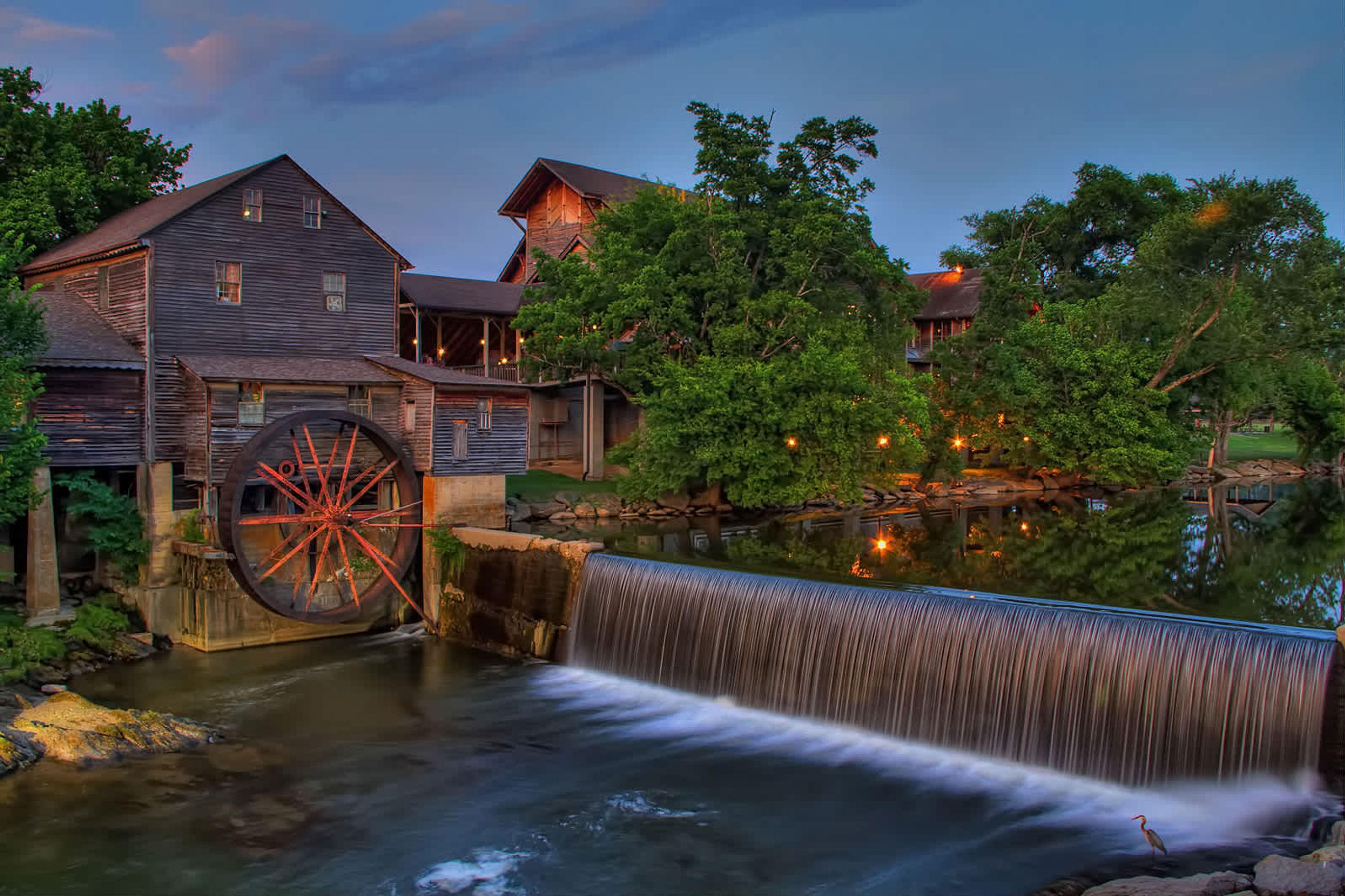 A historic building with a large water wheel and a waterfall.
