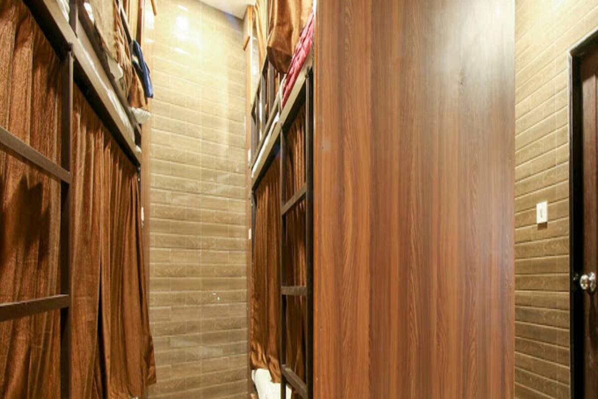 A hotel room with wooden bunk beds, a tiled floor, and a wooden door.