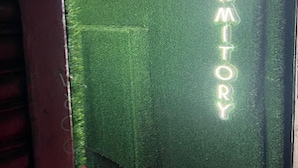 A neon sign spelling "DORMITORY" on a textured wall. - Negasi Dormitory (Mumbai)