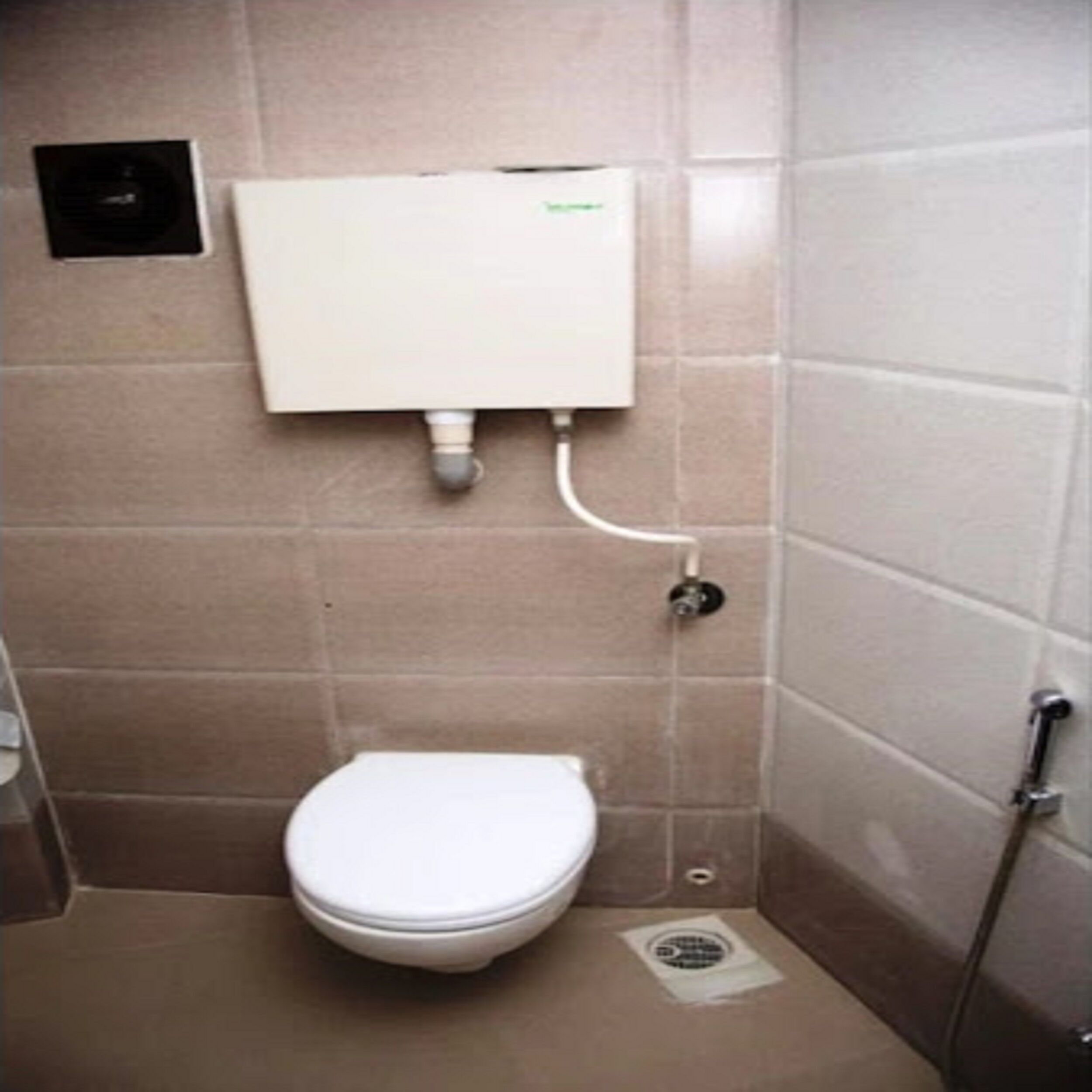 A small, tiled bathroom with a toilet, a wall-mounted water heater, and a shower area.